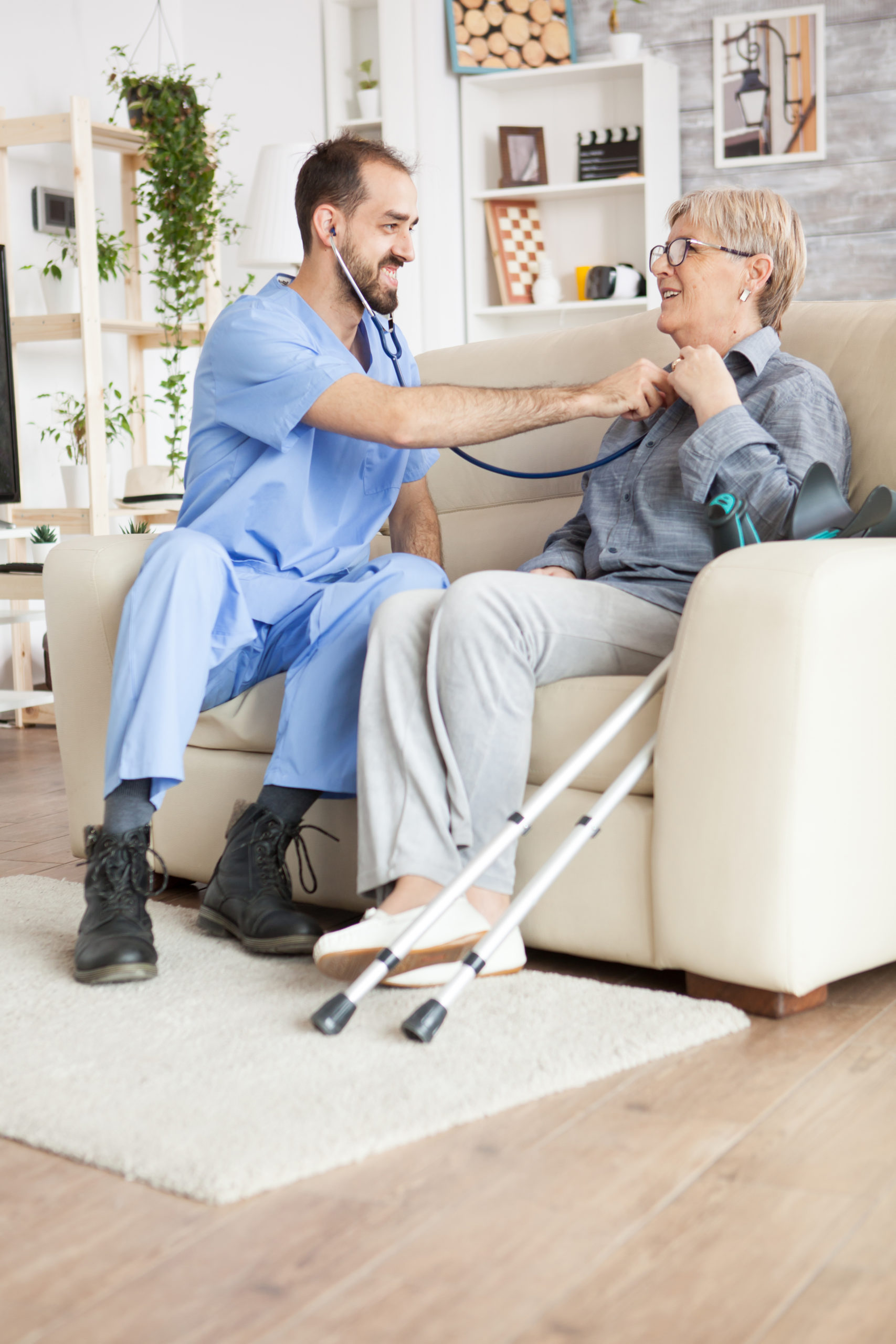 Young doctor using stethoscope to listen old woman heart beat